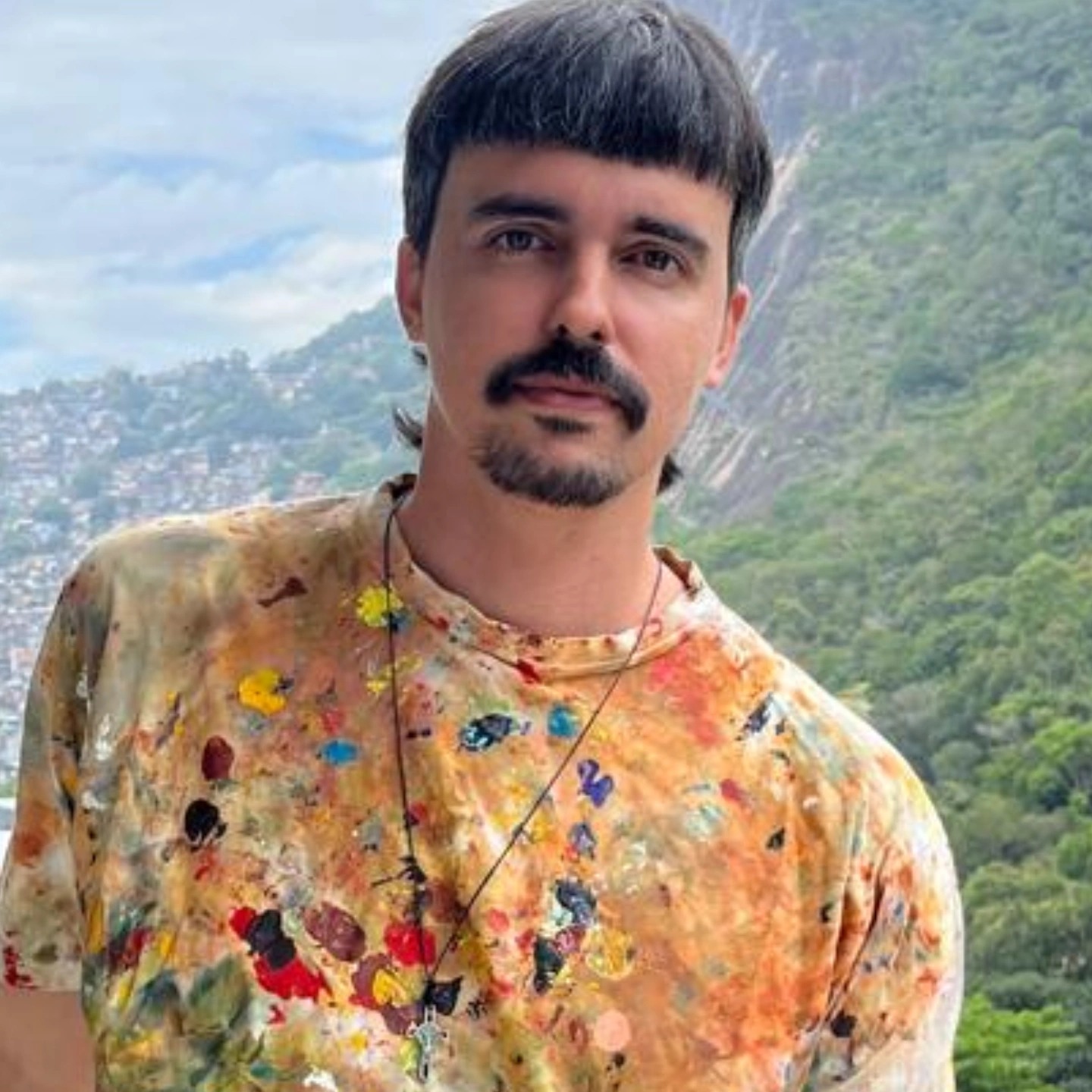 Retrato de Gabriel Paz, artista e professor de pintura e desenho em Botafogo, vestindo camiseta com respingos de tinta, no Rio de Janeiro.