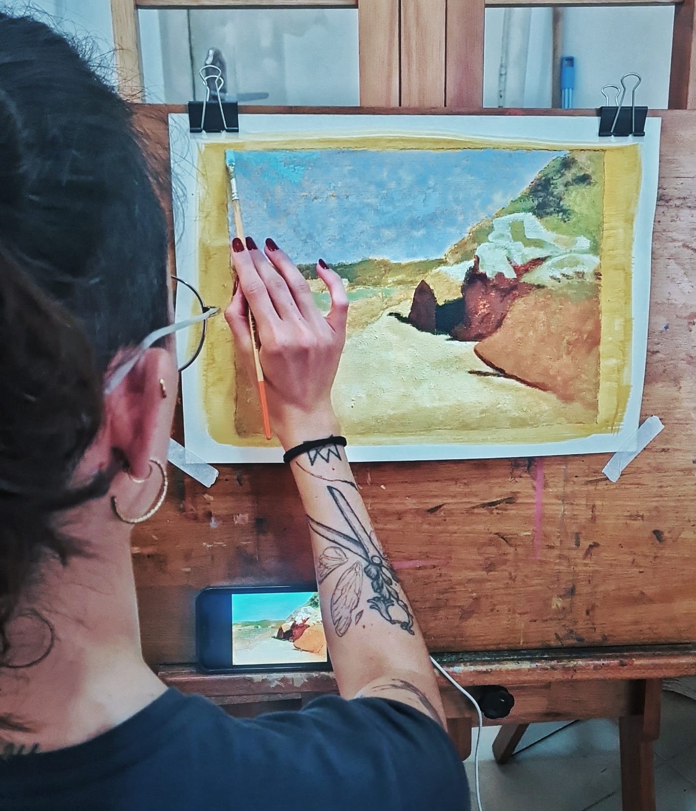Pintura monocromática em azul de um barco encalhado próximo a uma construção, trabalho de aluno do atelier.